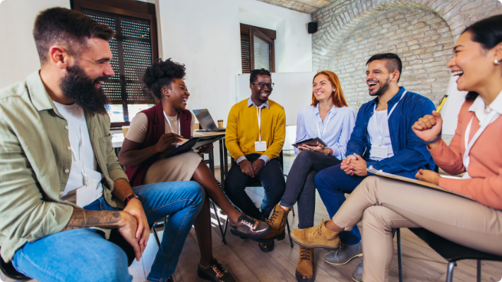 Six people in a semi-circle laughing and learning in an office Six people in a semi-circle laughing and learning in an office