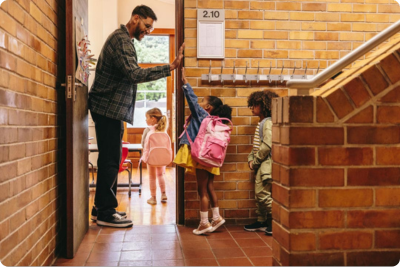Teacher high-fiving students as they enter classroom