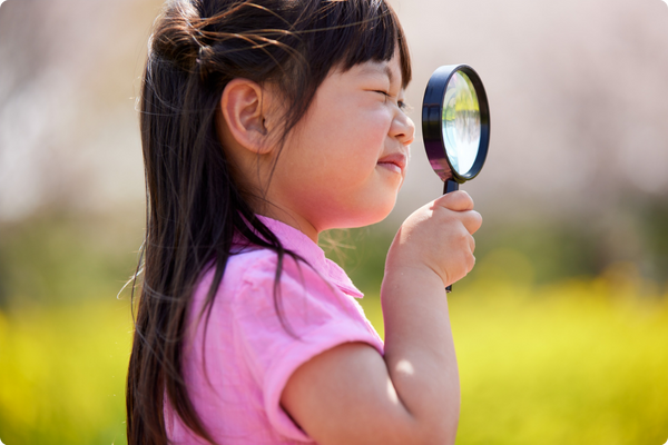 Young student outside looking through a magnifying glass Young student outside looking through a magnifying glass